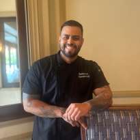 Man, Black Chef Coat, Dark Hair, Leaning on a chair