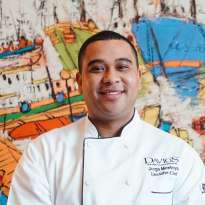 Man, White Chef Coat in front of a painting of boats in Madrid