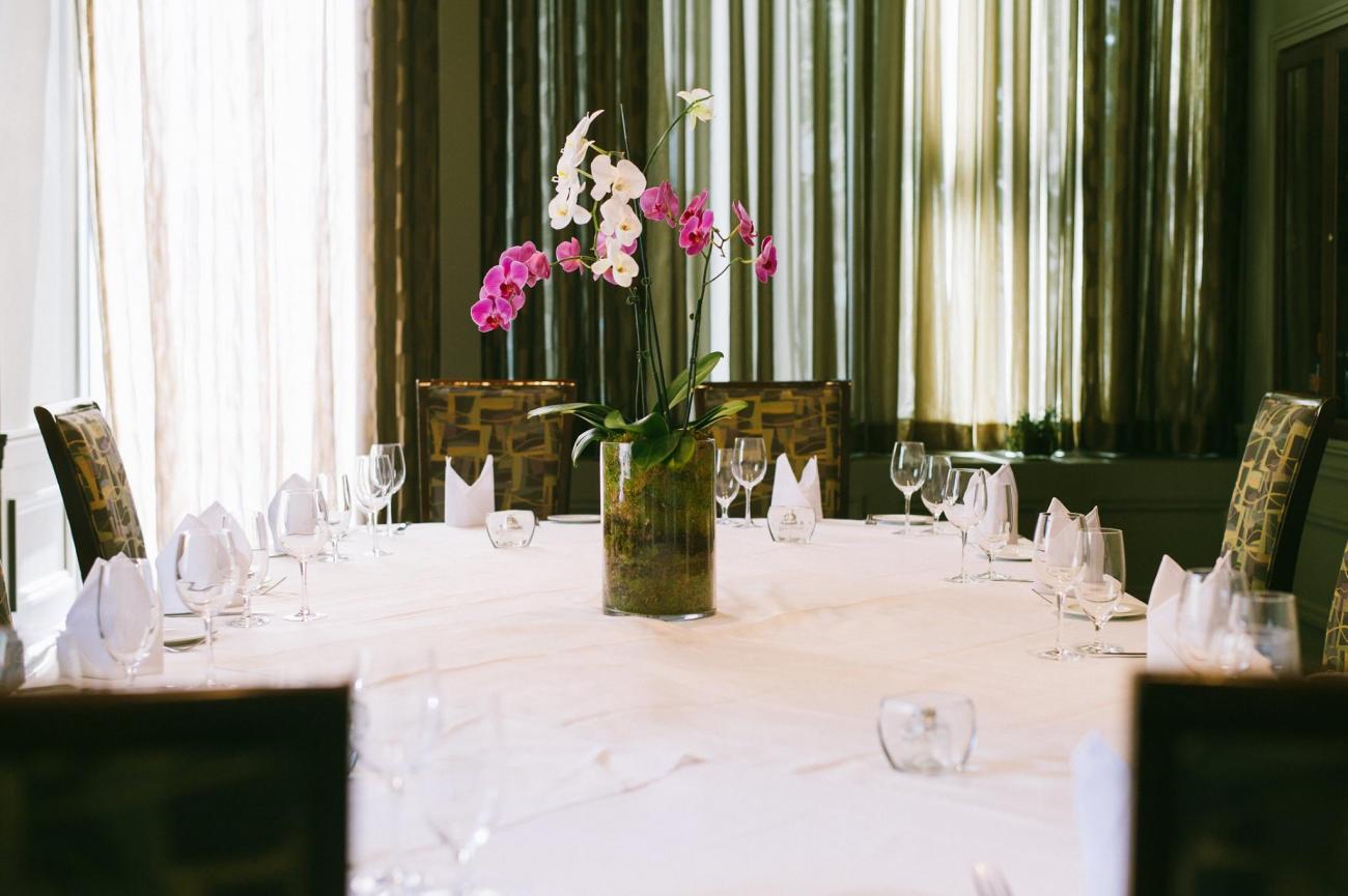 Table set for eight with white tablecloth and a centerpiece of pink orchids